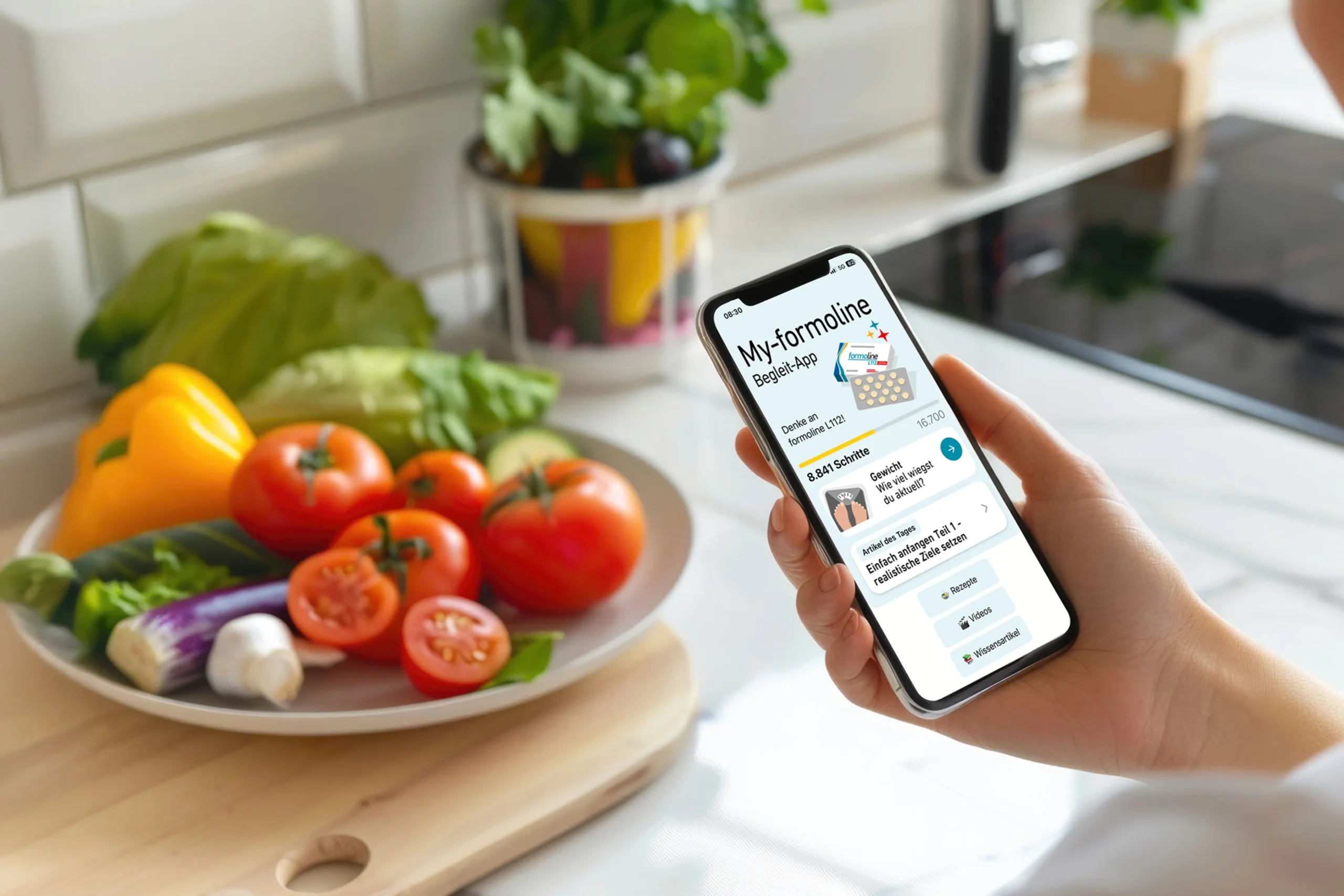 Smartphone mit der My-formoline Begleit-App neben frischem Gemüse in einer Küche zur Unterstützung von Intervallfasten, Ernährung und Gewichtsmanagement.